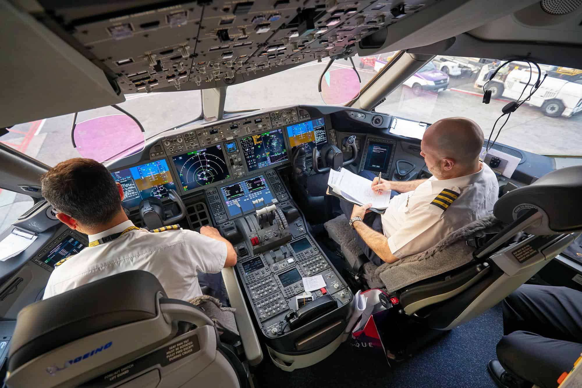 Two airline pilots inside a modern commercial aircraft cockpit, conducting pre-flight checks and reviewing documents, illustrating ATPL Air Law concepts such as operational procedures, regulations, and compliance.